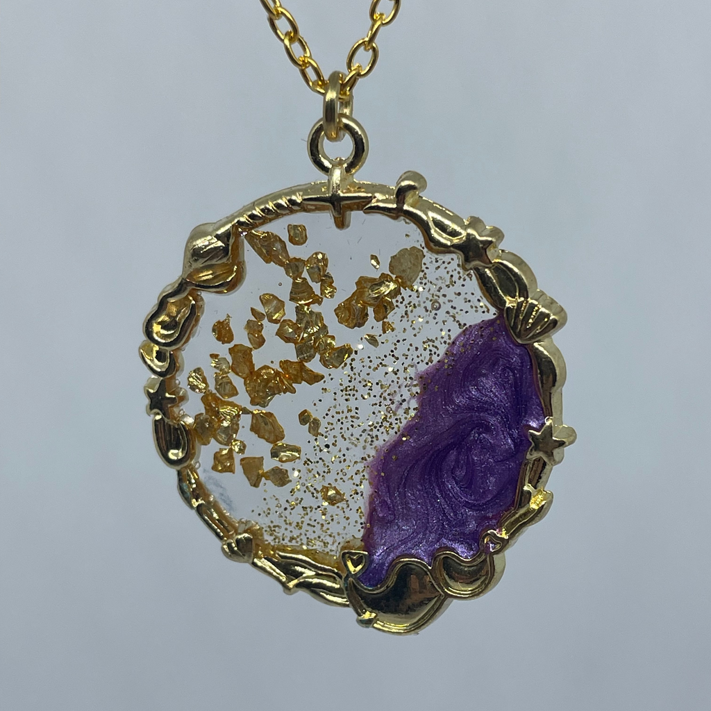Gold necklace with a purple pendant on a gray background