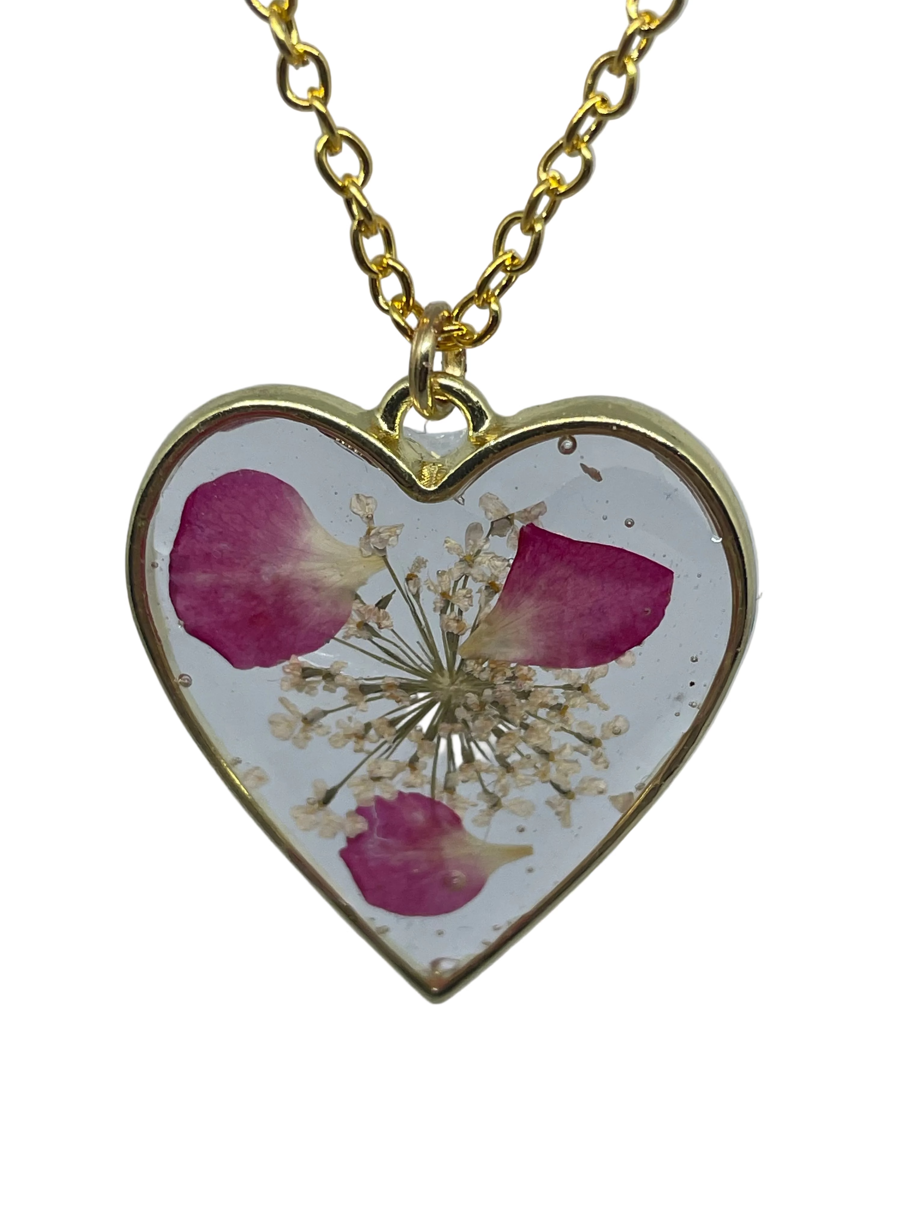 Heart-shaped pendant with pressed flowers on a gold chain against a light gray background