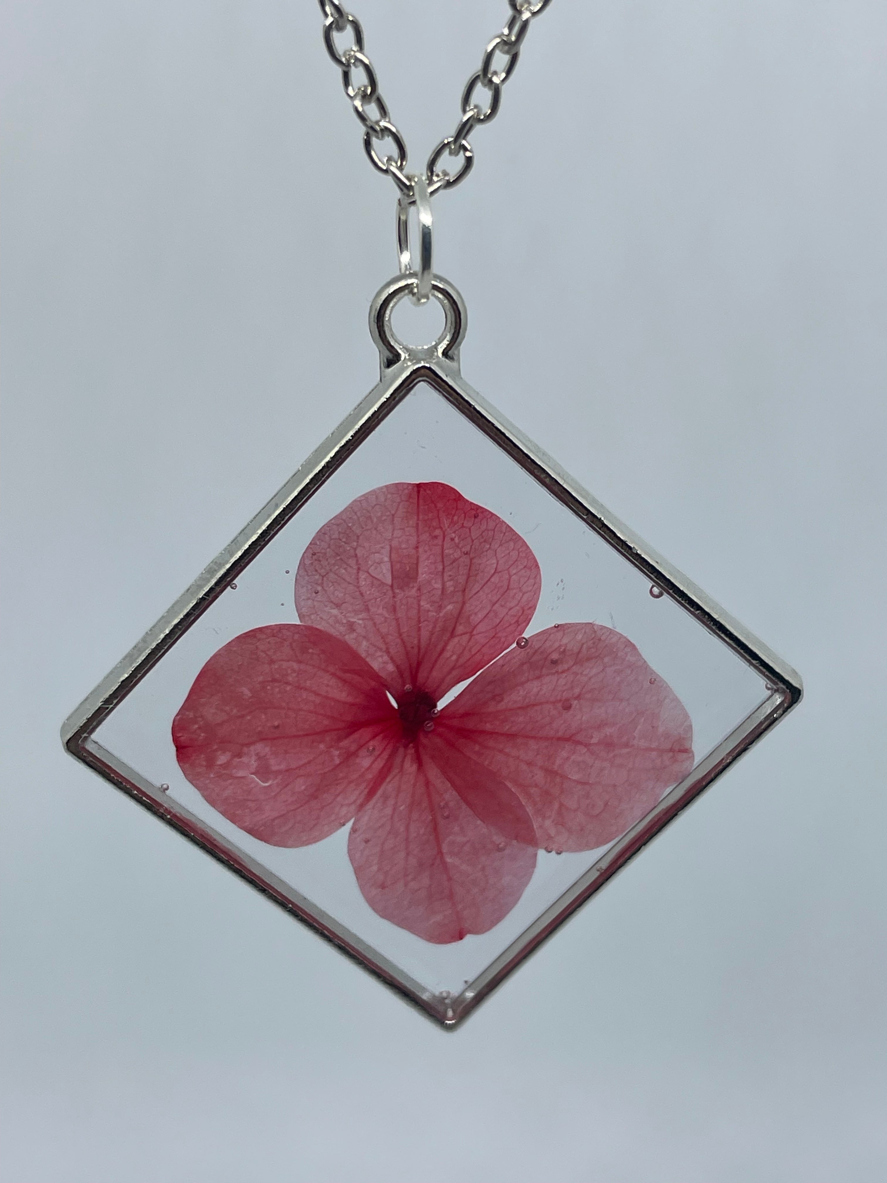 Necklace with a pink flower pendant on a light gray background