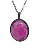 Pink rose pendant on a silver chain against a gray background