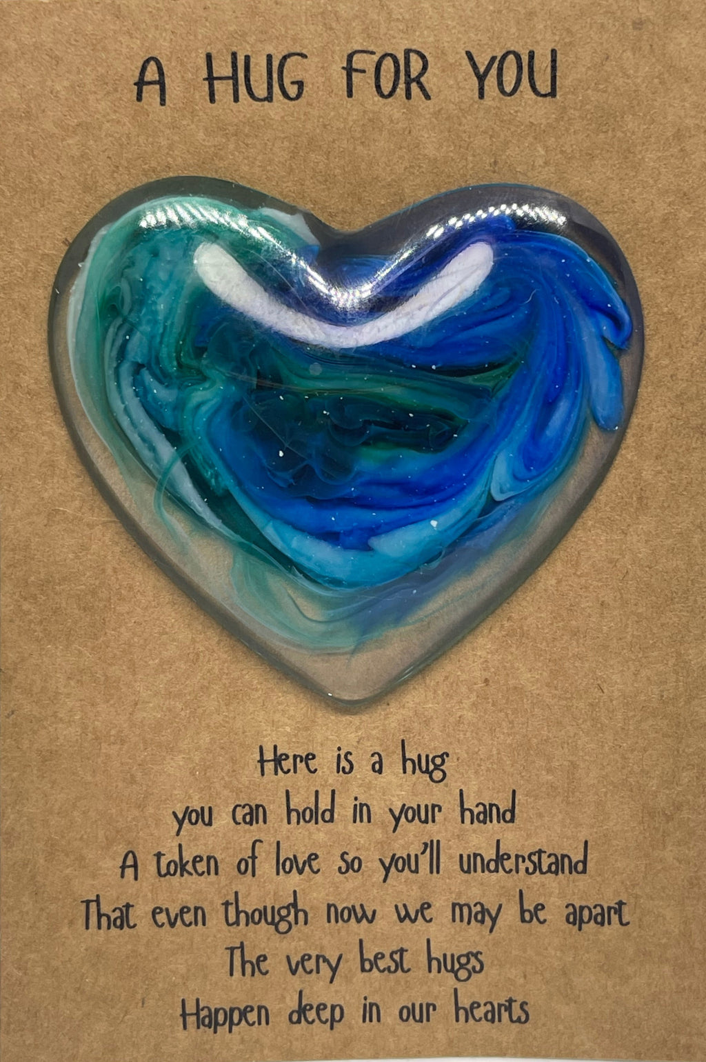 Heart-shaped blue and green resin object on a brown card with text