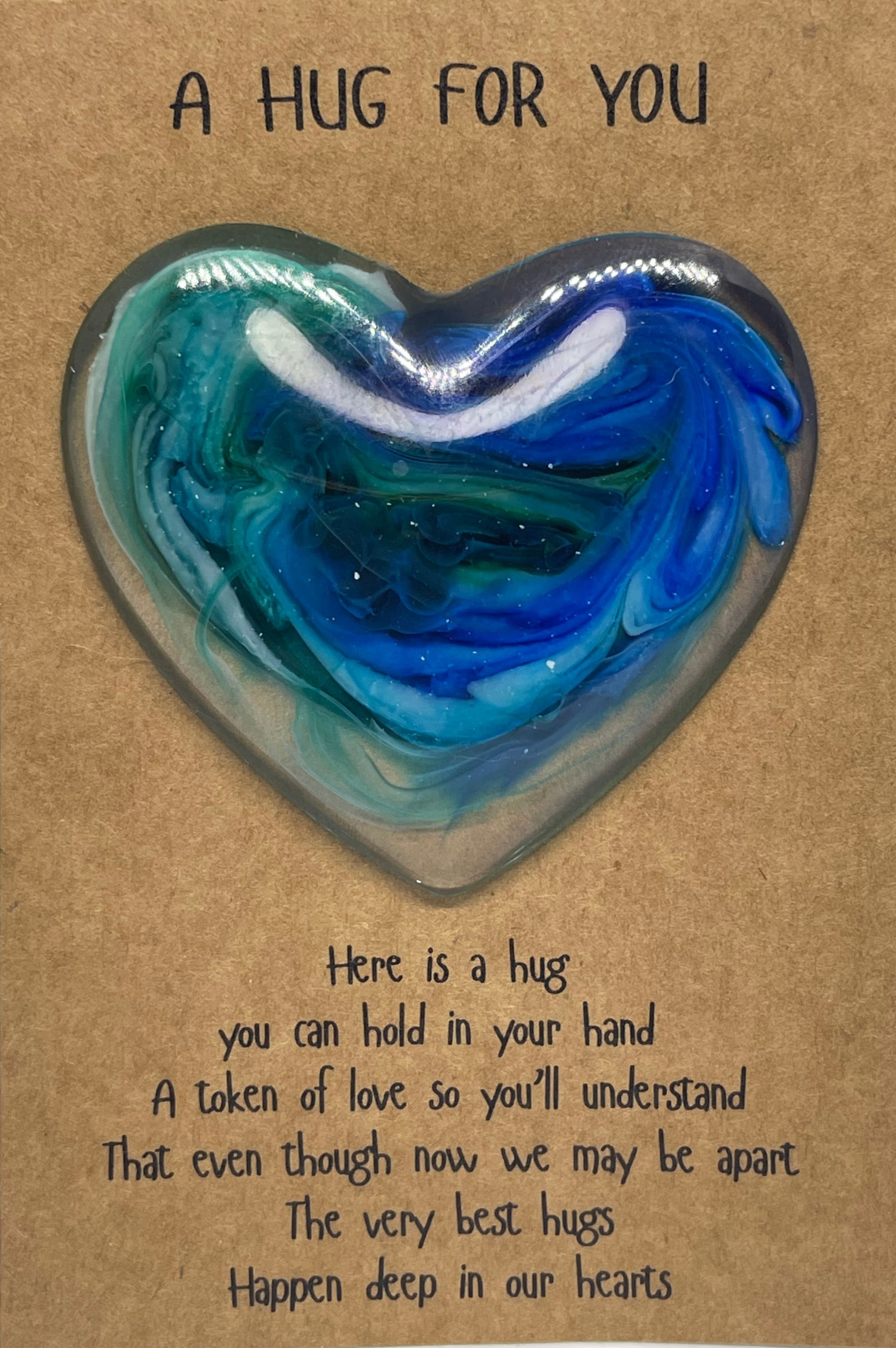 Heart-shaped blue and green resin object on a brown card with text