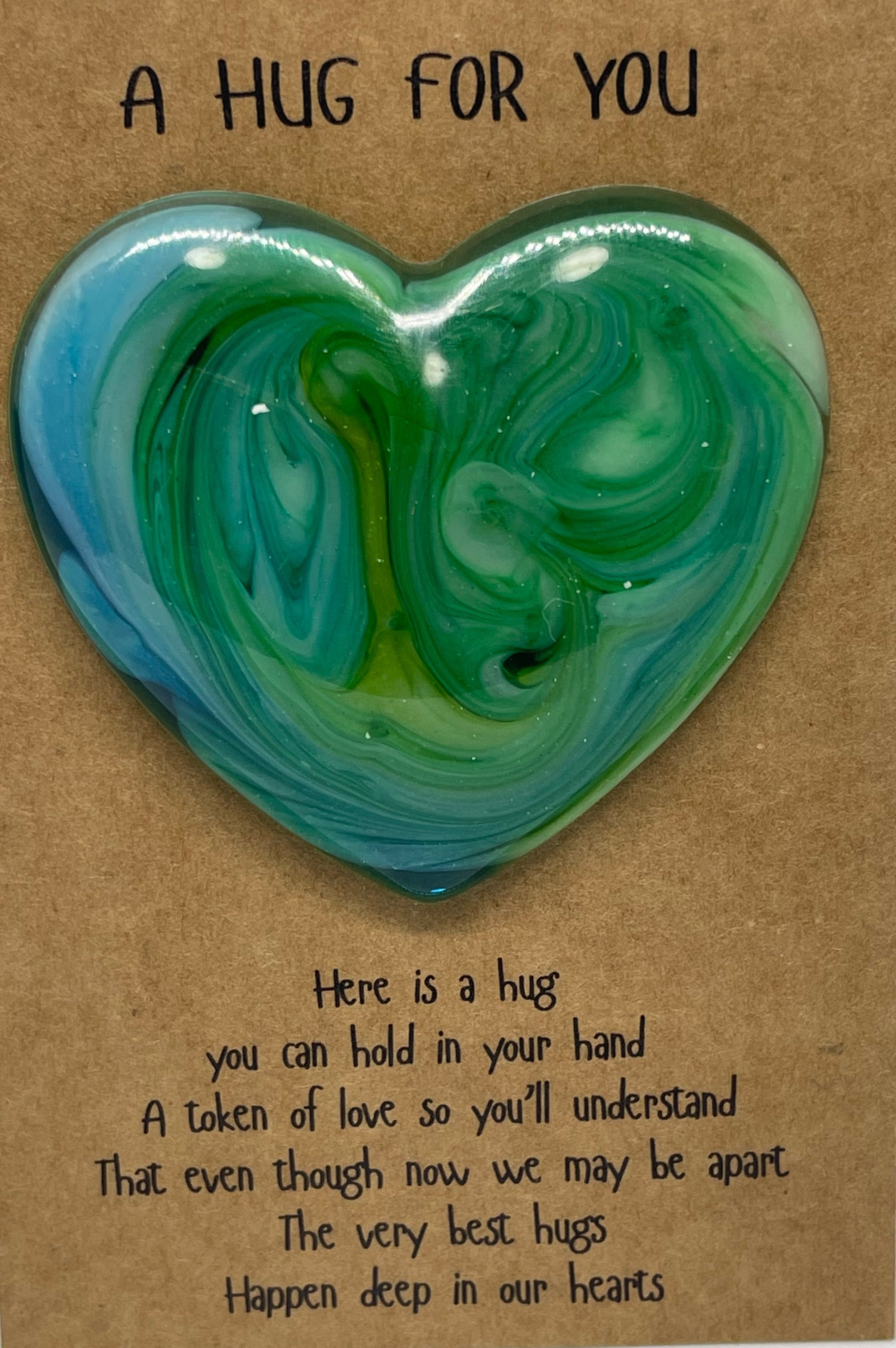 Heart-shaped green and blue resin object on a cardboard base with text